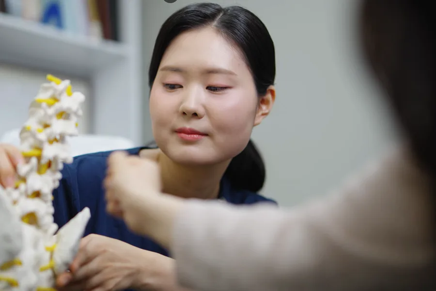 척추 모형으로 설명하며 상담하는 모습